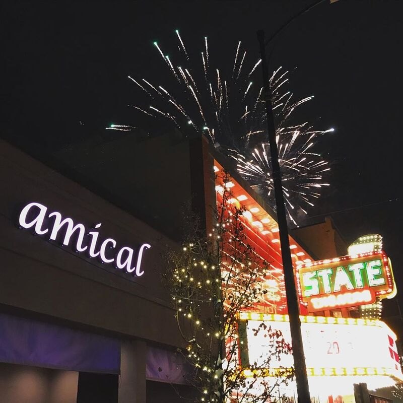 The Amical sign at night with the State Theatre marquee and fireworks behind it