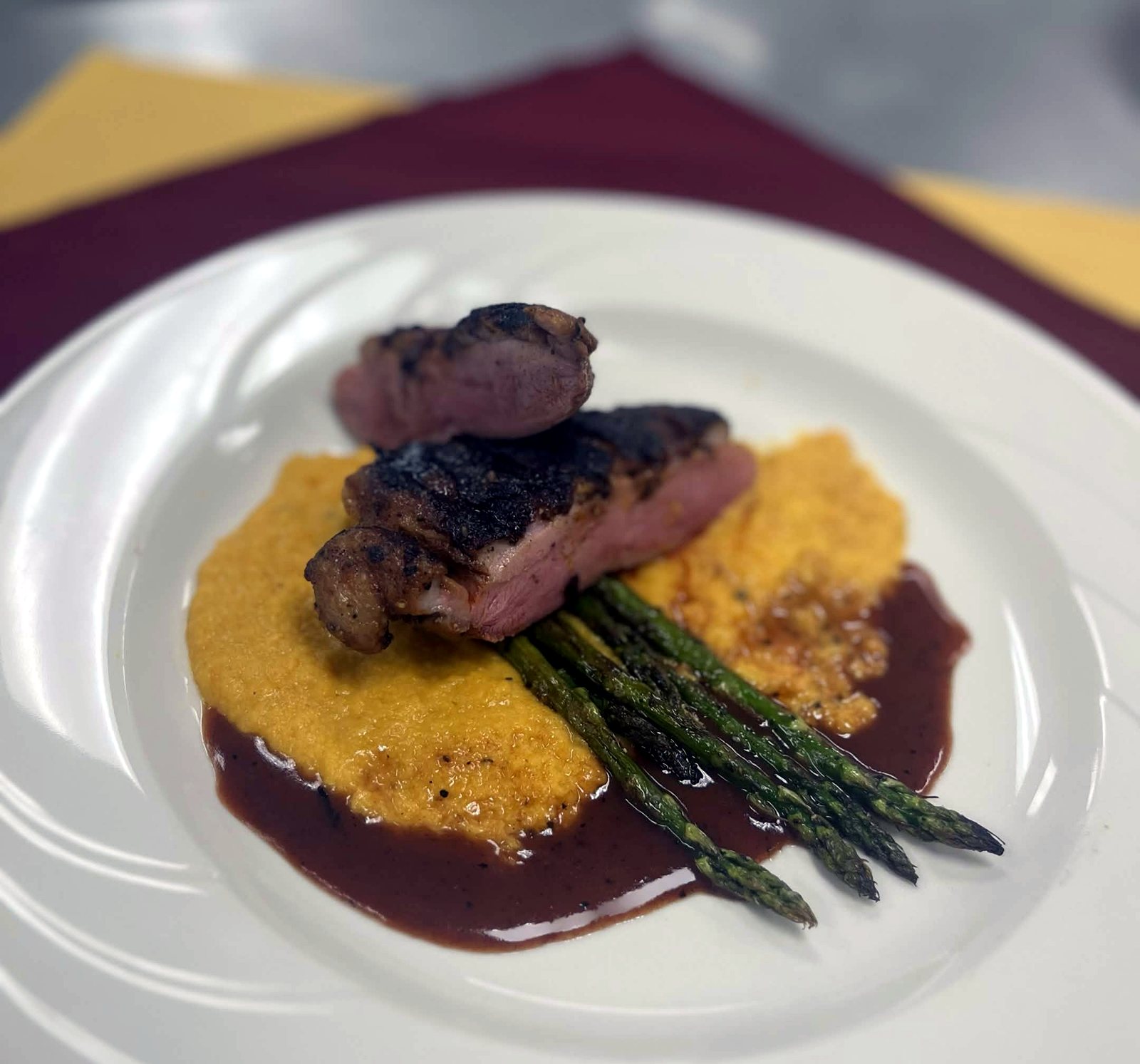 Sliced seared duck breast over sweet potato puree with asparagus and a dark sauce