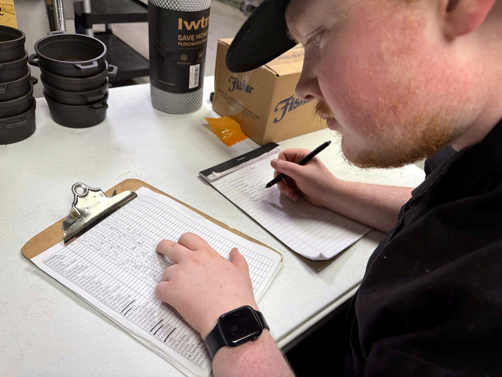 Alex writing on a prep list at a desk with a clipboard