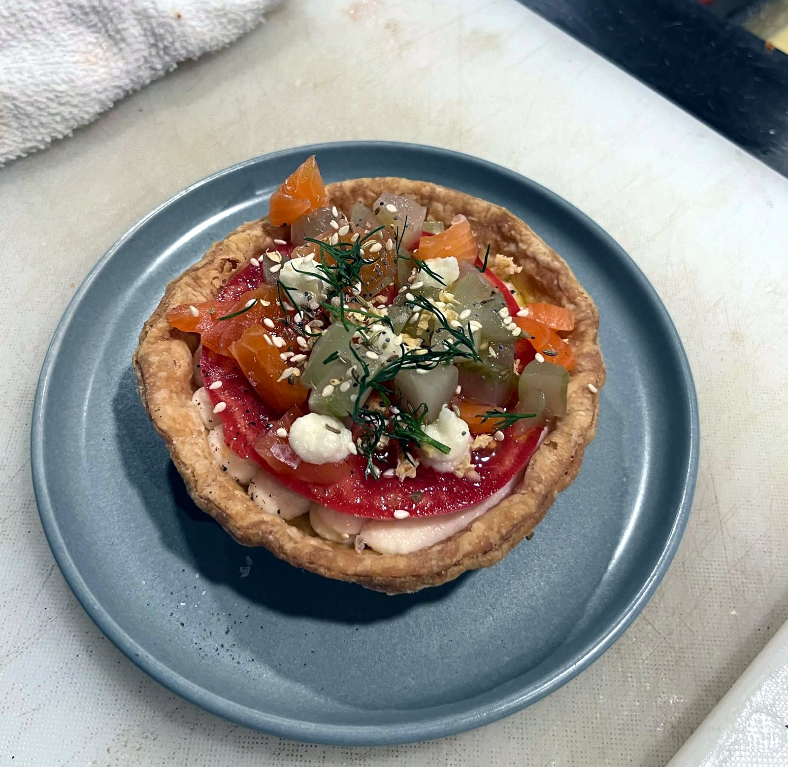 Tomato tart with cured salmon and dill on a blue plate