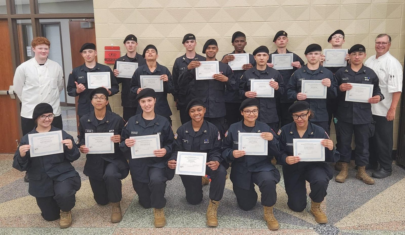 MYCA culinary cadets in uniform holding certificates with two instructors in chef coats
